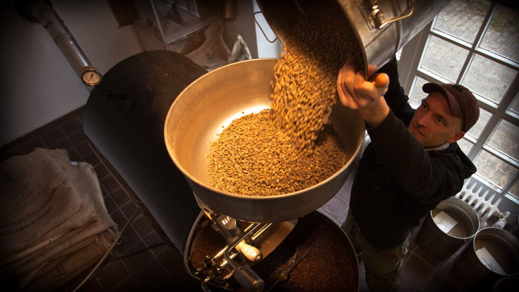 Michael Mrozek sch&uuml;ttet Rohkaffee in die R&ouml;stmaschine