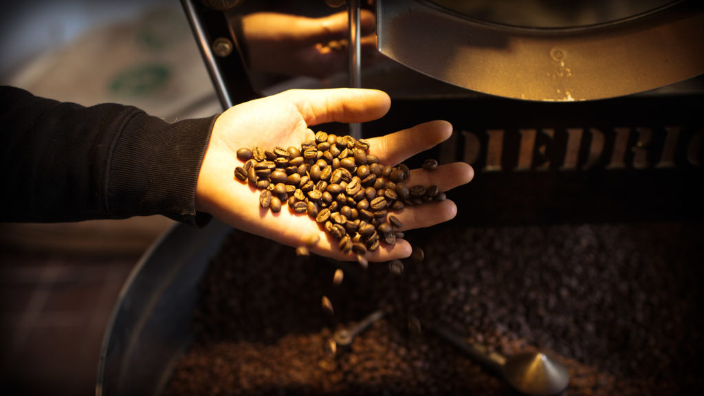 Frisch ger&ouml;stete Kaffeebohnen die warm durch die Finger gleiten