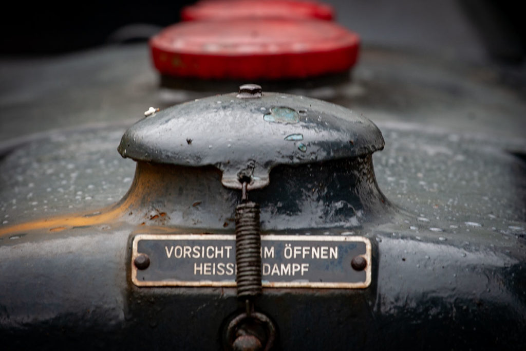 Metallschild an einem alten Traktor, auf dem steht: Vorsicht beim &Ouml;ffnen, hei&szlig;er Dampf