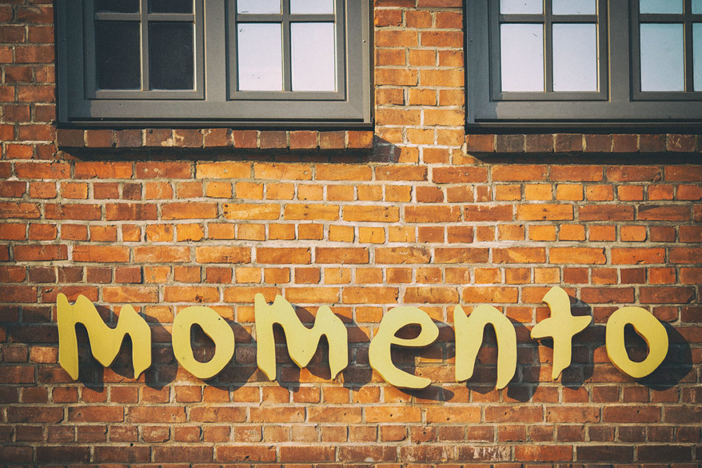 Backstein-H&auml;userwand mit Kassettenfenstern und der Aufschrift "momento"